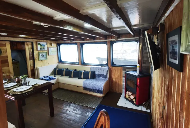 Saloon on Patagonia I: dining table, a sofa under the windows and a wood stove